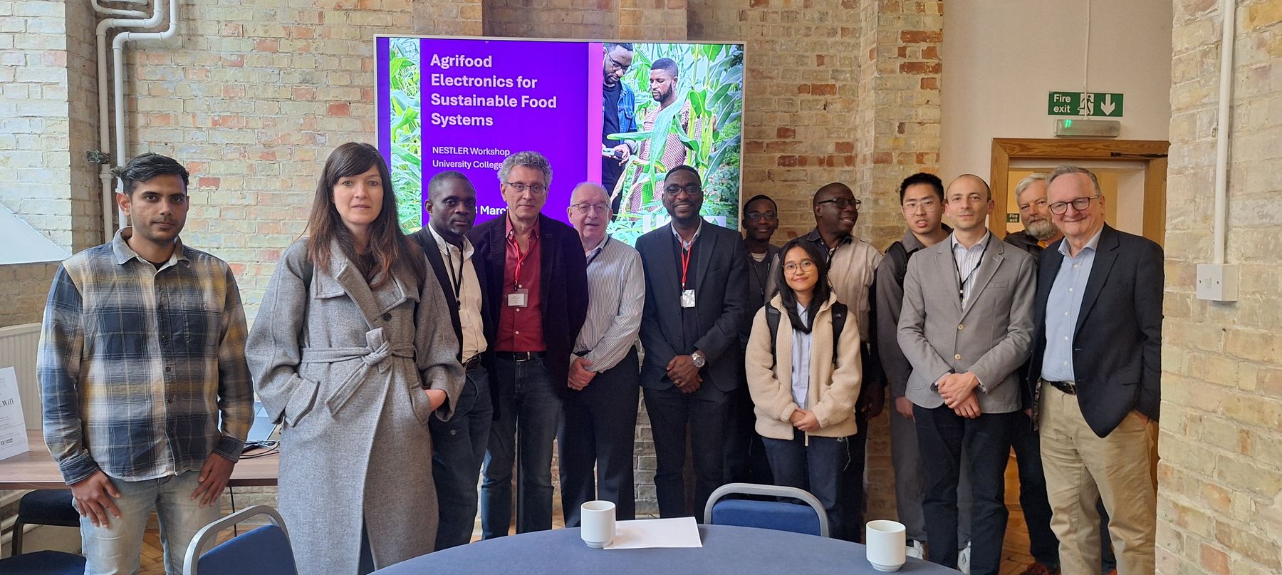 Group of workshop participants in front of a screen reading Agrifood Electronics for Sustainable Food Systems